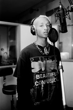 a young man wearing headphones standing in front of a microphone and recording equipment,