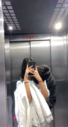 a woman taking a selfie in front of an elevator with her towel wrapped around her shoulders