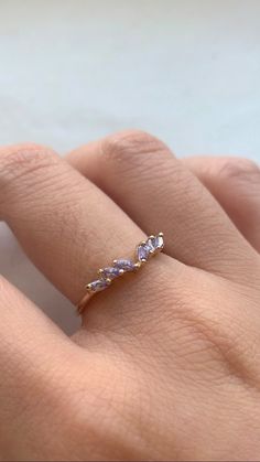 a woman's hand wearing a gold ring with three stones on it and one stone in the middle