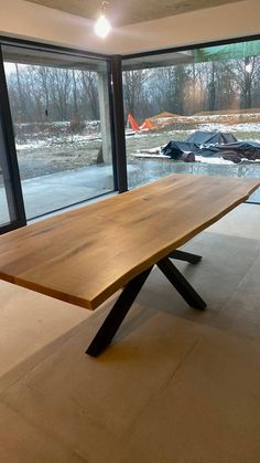 a large wooden table sitting in front of a sliding glass door that looks out onto a snowy field