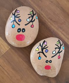 two painted rocks sitting on top of a wooden floor next to each other with different colored eyes