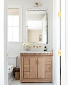 a bathroom with a sink, mirror and wooden cabinetry in it's center