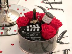 a bottle of wine and some red roses in a silver container on a table with a mirror