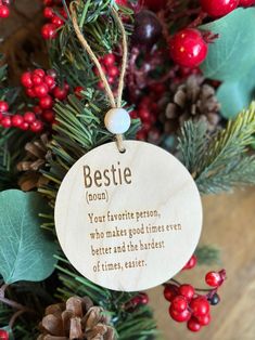 a wooden ornament hanging from a christmas tree filled with berries and pine cones