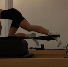 a woman is doing pivots on a stationary rowing machine while holding her leg in the air