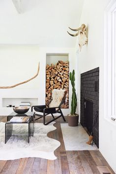 a living room filled with furniture and a fire place next to a pile of logs