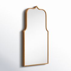 a mirror hanging on the wall with a wooden frame and an arch shaped like a door