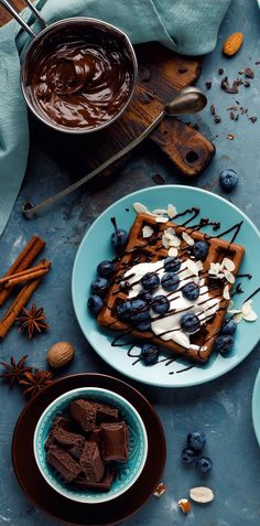 chocolate waffles with blueberries, almonds and whipped cream are on the table