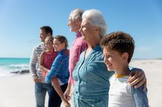 a group of people standing on the beach with their arms around each other - stock photo - images