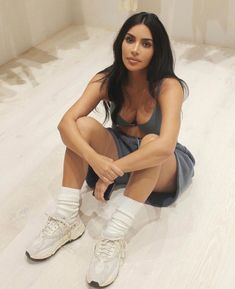 a woman is sitting on the floor with her legs crossed and wearing white boots,