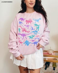 "This Unisex crewneck sweatshirt features a grunge set of dinosaur illustrations in a pastel color palette. It is the perfect gift for dinosaur lovers, present / future paleontologists, and more! Make sure to check out the other garment options below :) » O P T I O N S « ‣ Tshirt: https://www.etsy.com/listing/1699290791 » A B O U T « ‣ This item is made to order using direct-to-garment (DTG) printing technology. This digital process involves the printer inks being jetted or sprayed onto the text Casual Dinosaur Print Tops For Fall, Pink Dinosaur Print Crew Neck Top, Pink Crew Neck Top With Dinosaur Print, Casual Dinosaur Print Crew Neck Sweatshirt, Casual Dinosaur Print Tops For Streetwear, Casual Cotton Sweatshirt With Dinosaur Print, Cotton Dinosaur Print Tops For Streetwear, 90s Grunge Clothing, Soft Pastel Outfits