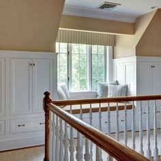 a room with white furniture and windows in the wall, along with wooden banisters