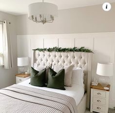 a bed with white headboard and green pillows