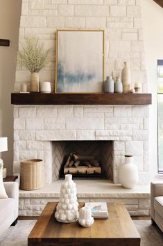 a living room filled with furniture and a fire place in front of a white brick wall