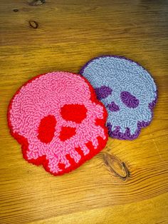 two crocheted skull coasters sitting on top of a wooden table