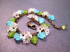 SALE Bracelet - was $26, now $23 Trios of frosty white acrylic blossoms (9mm) with aqua blue hearts and bright green glass leaves, along a 6mm link brass chain with a lobster claw clasp. Extra chain links make the bracelet adjustable up to nine inches in length. See more of my jewelry designs here: justCHARMING.etsy.com And please visit my sister~shop; justEARRINGS.etsy.com for earrings in all styles. Both of my jewelry shops offer FREE SHIPPING! Highlights: handmade jewelry, charm bracelet, brass chain, white flowers, aqua blue hearts, green leaves, women fashion gift, free shipping Flower Charm Bracelet, Boho Jewelry Diy, Czech Glass Jewelry, Green Bracelet, Beads Jewellery, Botanical Jewelry, Wrap Bracelets, Wire Art, Flower Charm