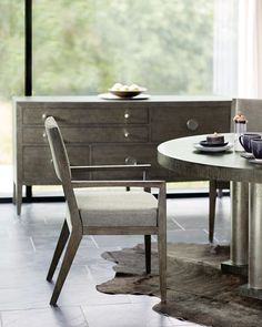 a dining room table with two chairs and a bowl on top of it, in front of a large window