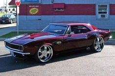 a maroon muscle car parked in front of a building