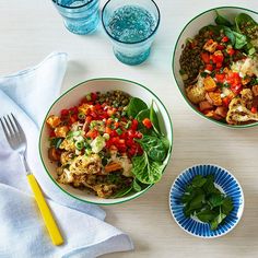 three bowls filled with different types of food on top of a wooden table next to glasses