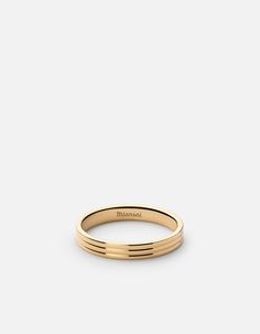 a gold wedding band with thin lines on the outside, in front of a white background