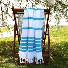 a blue and white striped towel sitting on top of a wooden chair in the grass