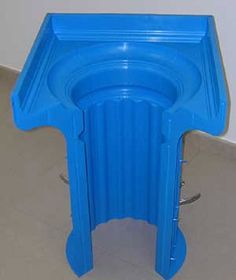 a blue stool sitting on top of a floor next to a white wall and tile floor