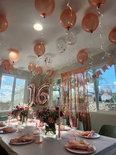 a table set for a party with balloons and streamers hanging from the ceiling over it