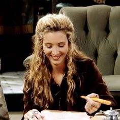 a woman sitting at a table writing on a piece of paper with a pen in her hand