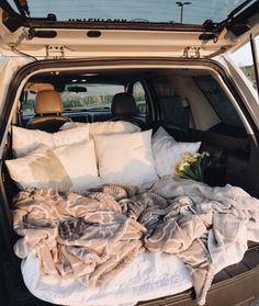 the back end of a car with blankets and pillows in it's trunk area