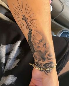 a person with a tattoo on their arm holding a cross in the palm of their hand