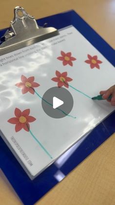 a clipboard with red flowers on it being held by someone's hand while holding a pen