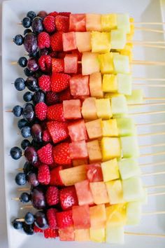 fruit skewers are arranged on a white plate