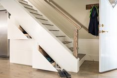 an open stair case in front of a white door with shoes on the bottom shelf