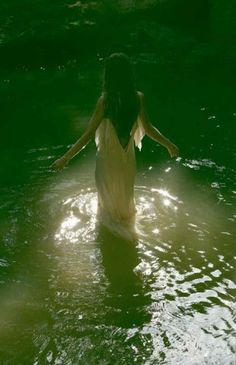 a woman standing in the water with her arms outstretched