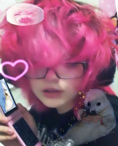 a girl with pink hair and glasses holding a cell phone in her hand while looking at the screen