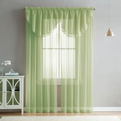 a living room with green curtains and a rug