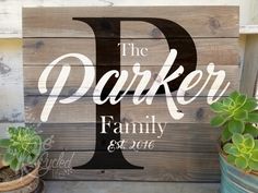 a wooden sign that says the parker family and two potted succulents