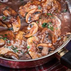 a pan filled with meat and mushrooms covered in gravy on top of a table