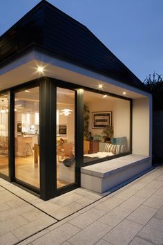 an open living room and dining area with glass doors on the outside, lit up at night