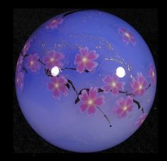 a blue glass ball with pink flowers painted on it