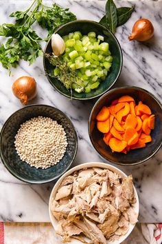 bowls filled with food sitting on top of a marble counter next to onions, carrots and celery