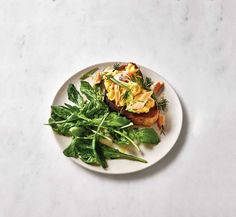 a white plate topped with green vegetables and toast