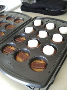 two muffin tins with marshmallows and chocolate in them sitting on a counter