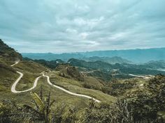 a winding road in the middle of a lush green mountain range with trees on both sides