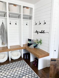 a mud room with white walls and wood flooring, shelving units on the wall