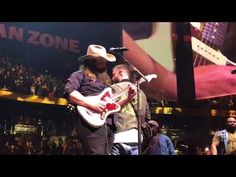 a man with a guitar standing in front of a microphone and another man wearing a cowboy hat