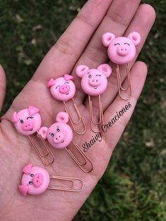 five pink pig clips in the palm of someone's hand that is holding them