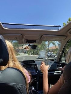 two people sitting in the back seat of a car, one holding a drink and the other driving