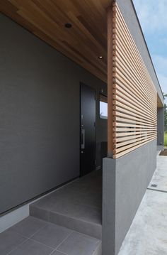 the front entrance to a modern home with wood slats on the wall and concrete steps