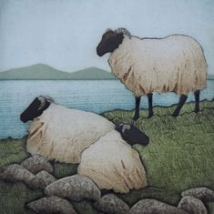 two sheep standing on top of a grass covered hill next to water and rocks with mountains in the background